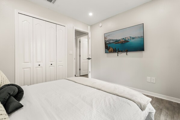 A bedroom with a bed, white wardrobe, and a painting of a landscape. - Luxe Hideaway 3BR/2BA Full Privacy/ Pool/Backyard (Kissimmee)