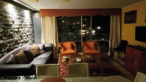 A living room with a sofa, two armchairs, a glass coffee table, and a TV on a cabinet. - Spacious Apartment in Algarrobo in Laguna Vista with Ocean / Sea view (Algarrobo)