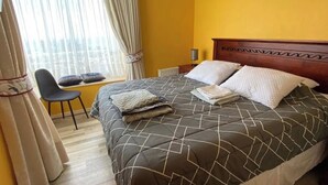 A bedroom with a bed, a chair, a window with curtains, and a radiator. - Spacious Apartment in Algarrobo in Laguna Vista with Ocean / Sea view (Algarrobo)