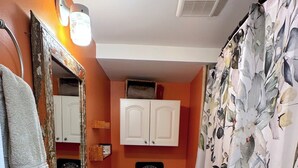 A bathroom with a white sink, a toilet, a mirror, and a shower curtain with a floral pattern.