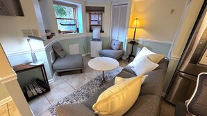 A compact living space with a sofa, a small round table, a bookshelf, and a lamp.