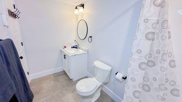 Een kleine, schone badkamer met toilet, wastafel en een douchegordijn met een cirkelpatroon.