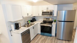 A modern kitchen with white cabinets, stainless steel appliances, a dishwasher, and a built-in oven.