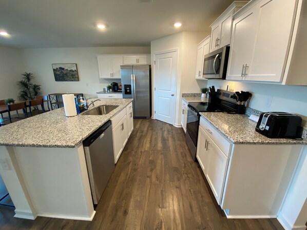 A modern kitchen with granite countertops, stainless steel appliances, and white cabinetry.
