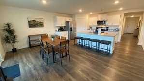 Una cocina moderna con una mesa de comedor de madera, taburetes de bar y una isla central.