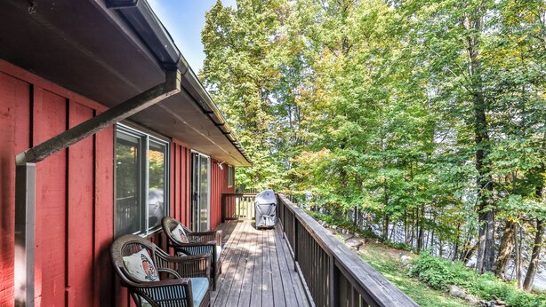 A wooden deck with outdoor furniture, overlooking a forested area. - Quite Lakefront Home on UTV/ATV/Snowmobile trails.  Dog Friendly! (Mercer)