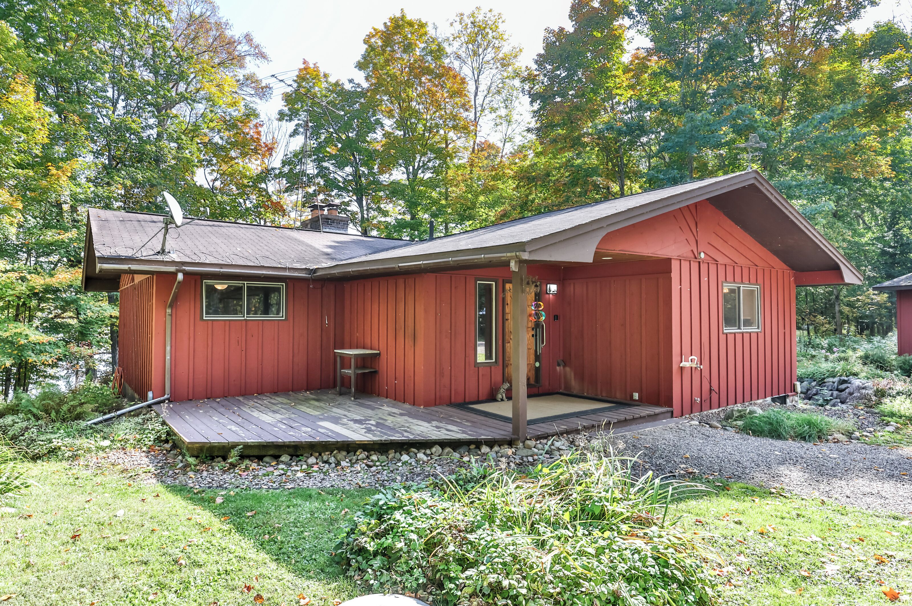 A red cabin with a wooden deck, a small table, and a window.