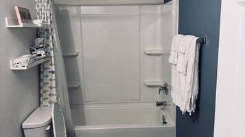 Een douche, handdoeken, zeep, toiletpapier