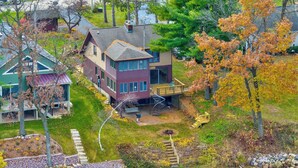 Une maison à deux étages avec une terrasse et un étang au premier plan.