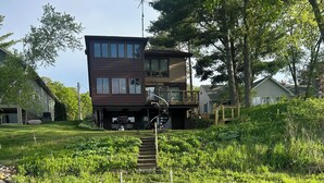 Eine Holzsteg, der zu einem Haus mit einem Balkon im zweiten Stock und einer Wendeltreppe führt.