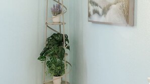 A corner room with a tall, spiral plant stand against a light blue wall, a framed painting above it, and wooden flooring. - Walk to DTLB, RetroRow, & Beach! (Long Beach)