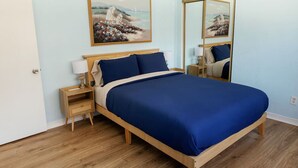 A bedroom with a bed, nightstands, a mirror, and a painting on the wall. - Walk to DTLB, RetroRow, & Beach! (Long Beach)