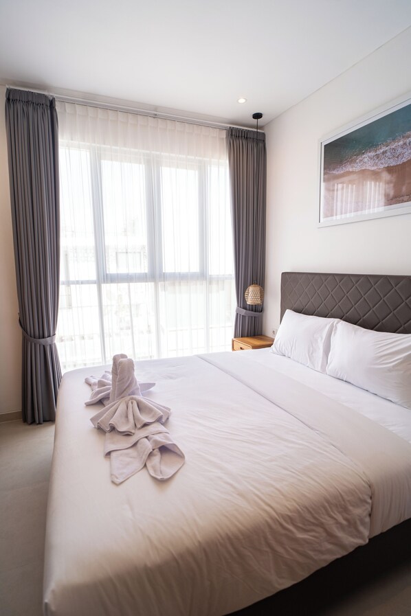 Una habitación de hotel con una cama grande, una mesita de noche, una lámpara y un cuadro en la pared.