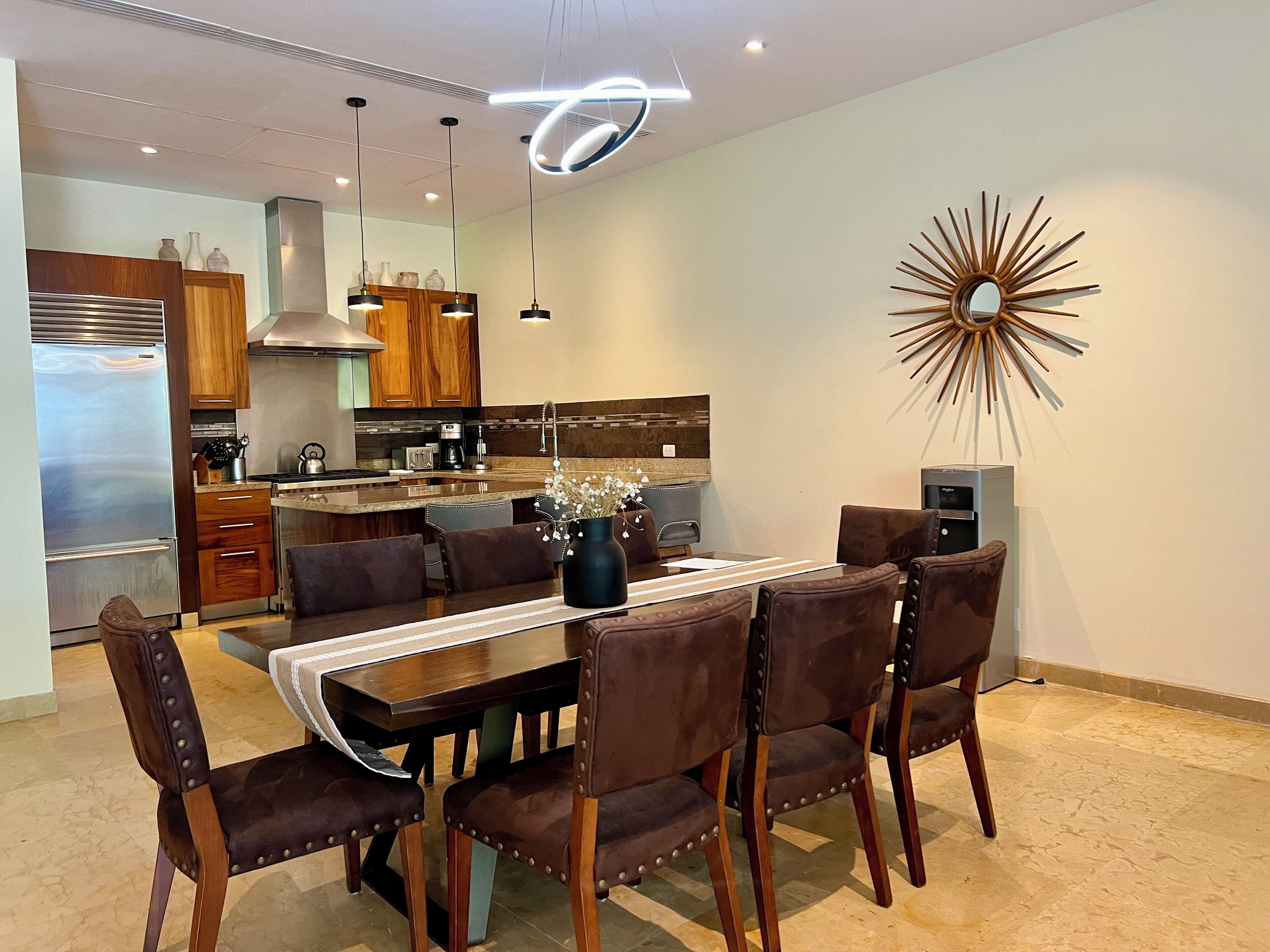 Una cucina moderna con mobili in legno, elettrodomestici in acciaio inossidabile e un'area pranzo con tavolo e sedie.