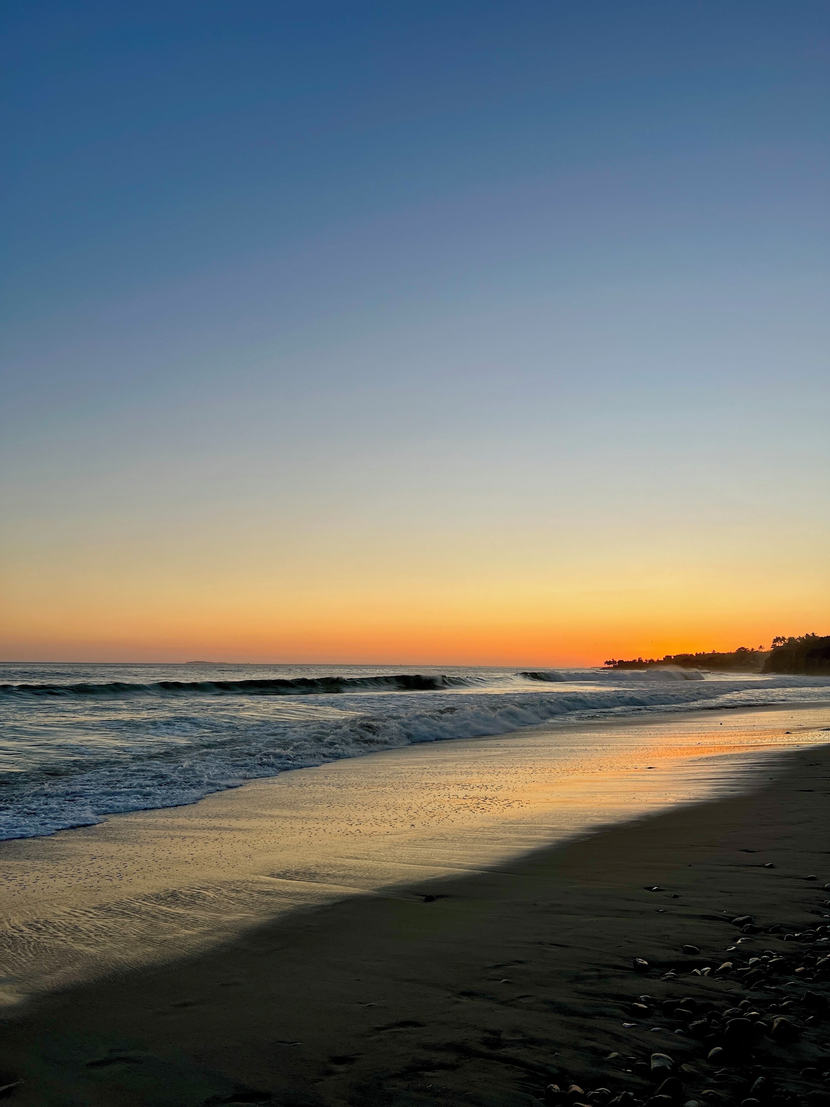 Uma praia com ondas ao pôr do sol.