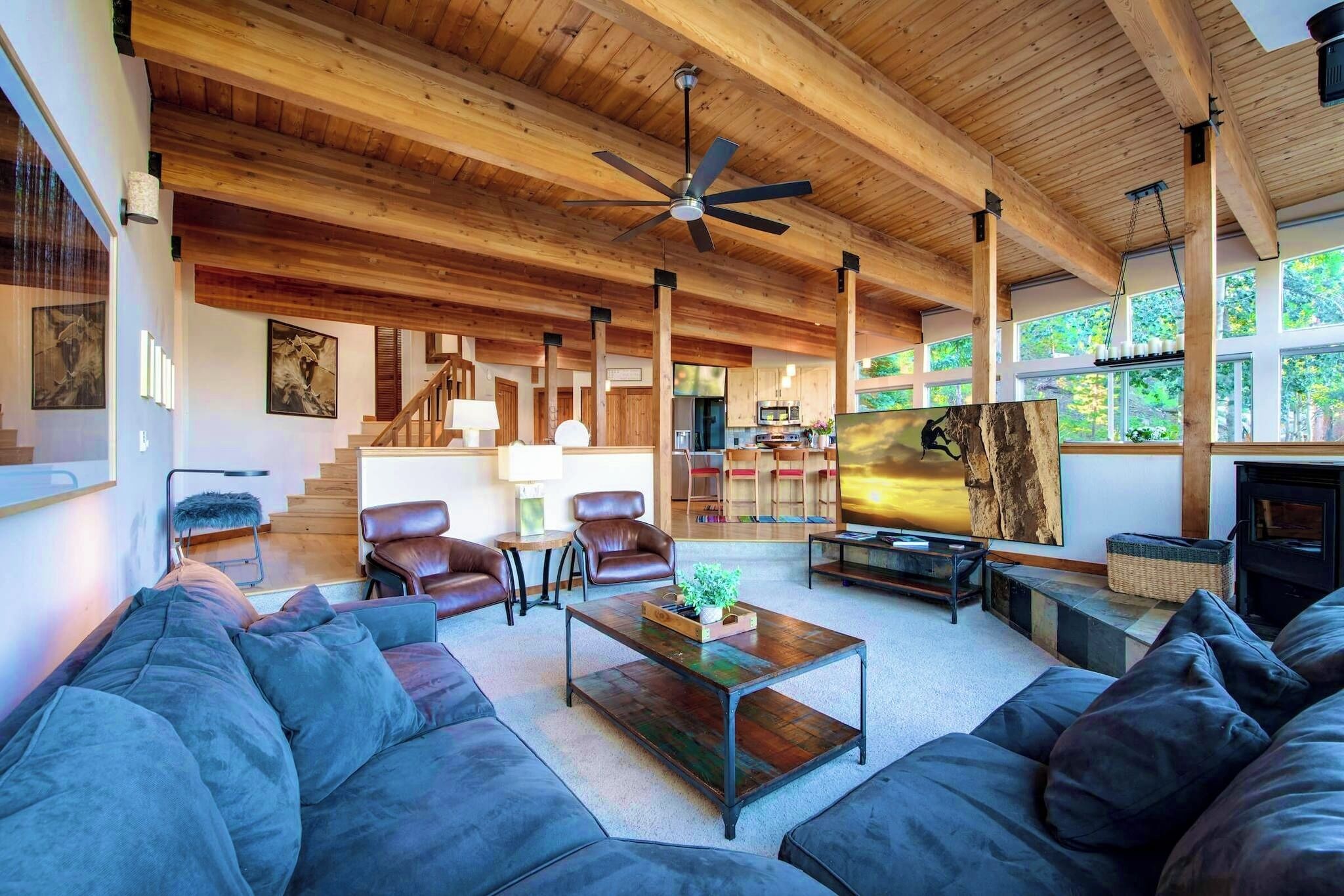 A spacious living room with a high ceiling, wooden beams, a large sofa, a coffee table, and a fireplace.