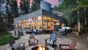 Ein modernes Haus mit Terrasse, Gartenmöbeln und einem Feuerkorb.