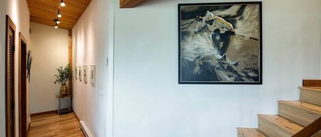 A wooden staircase with a framed painting of a horse on the wall.