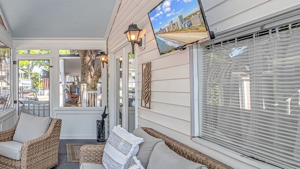 A covered porch with wicker furniture, large windows, and an American flag. - Ocean Lakes, Beach, Seasonal Waterpark, Indoor/Outdoor Pool, Arcade, Cafés, Golf (Myrtle Beach)