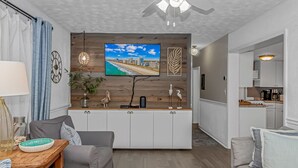 A modern living room with a TV, a dining area, and a kitchen. - Ocean Lakes, Beach, Seasonal Waterpark, Indoor/Outdoor Pool, Arcade, Cafés, Golf (Myrtle Beach)