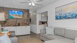 A modern living room with a grey sofa, a coffee table, and a TV mounted on the wall. - Ocean Lakes, Beach, Seasonal Waterpark, Indoor/Outdoor Pool, Arcade, Cafés, Golf (Myrtle Beach)