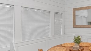 A dining area with a round table, woven placemats, a central plant, and a mirror on the wall. - Ocean Lakes, Beach, Seasonal Waterpark, Indoor/Outdoor Pool, Arcade, Cafés, Golf (Myrtle Beach)