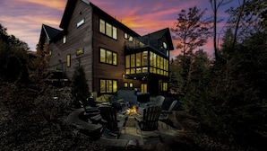 A modern two-story house with a fire pit in the backyard, surrounded by outdoor furniture. - 330 South Peak - Hot Tub - Timbertown Lift - Pemi River Access - Loon Mtn (Lincoln)