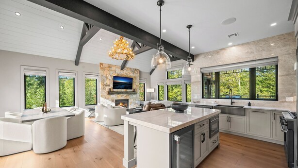 A modern kitchen with a large island, built-in appliances, and a stone fireplace. - 330 South Peak - Hot Tub - Timbertown Lift - Pemi River Access - Loon Mtn (Lincoln)