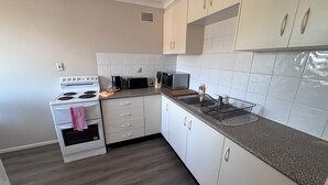 Une cuisine moderne avec des meubles blancs, une cuisinière, un four à micro-ondes et un grille-pain.