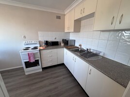 Una cocina moderna con armarios blancos, una estufa, un microondas y un tostador.