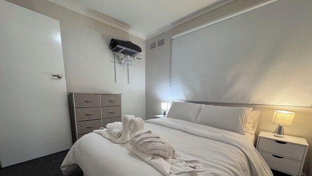 Une chambre d’hôtel équipée d’un lit, d’une commode, d’une table de chevet et d’un climatiseur fixé au mur.