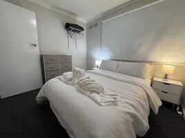 Habitación de hotel con cama, cómoda, mesita de noche y aire acondicionado de pared.