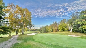 A golf course with a clear path, sand bunkers, and a variety of trees. - Bear Hills Retreat with Scenic Fairway Views (Hill City)