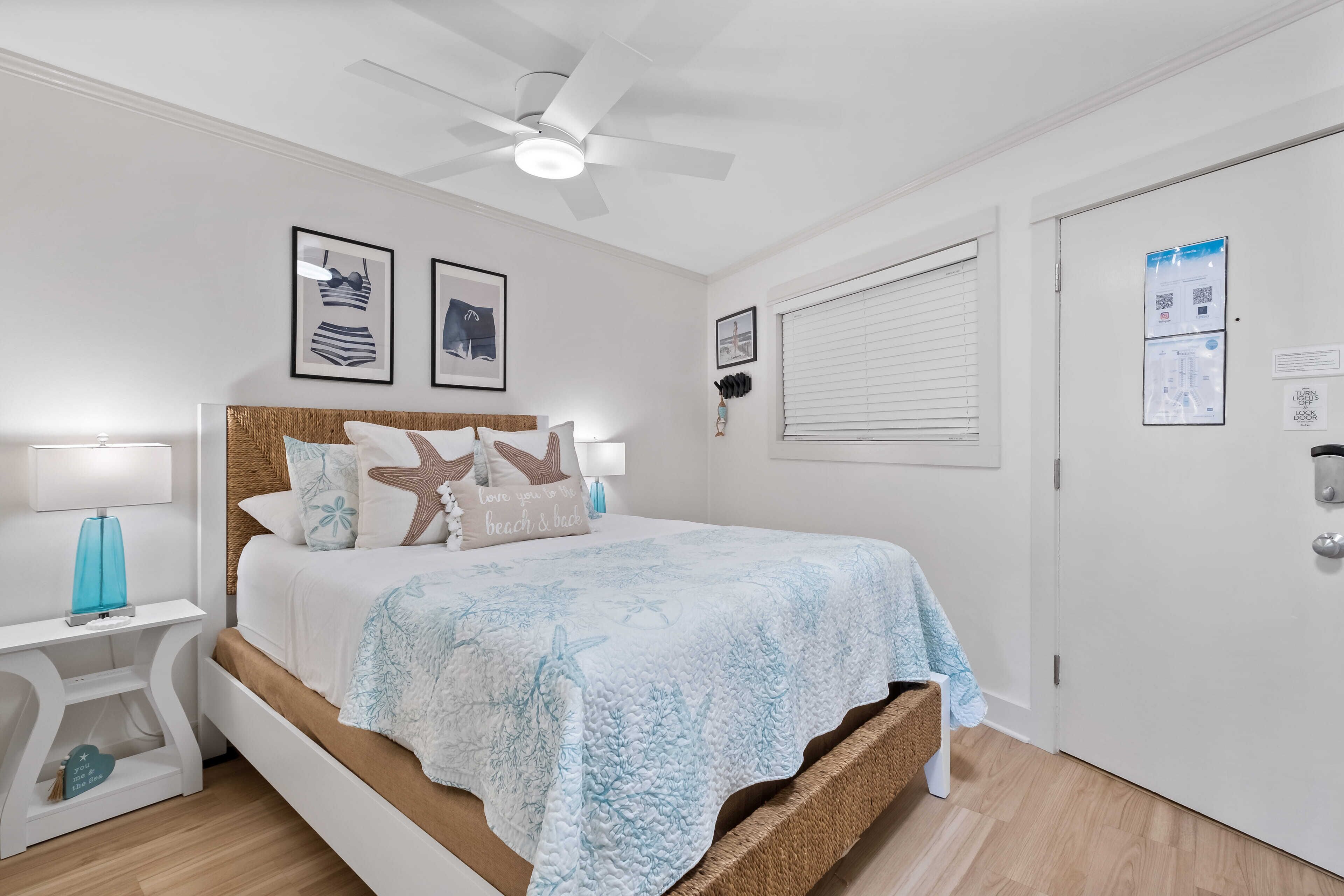 Une chambre à coucher comprenant un lit, une table de chevet, un ventilateur de plafond et une porte dotée d’un code QR.