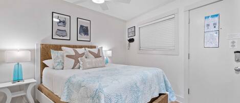 Une chambre à coucher comprenant un lit, une table de chevet, un ventilateur de plafond et une porte dotée d’un code QR.