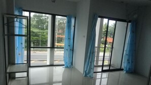 A room with large windows, a metal shelf, and a tiled floor.