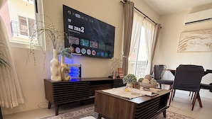 A living room with a flat-screen TV, a coffee table, a sofa, a rug, and a plant. - Balaycation 3 BR, 2BA, 5 Beds, sleeps 8 (Davao City)