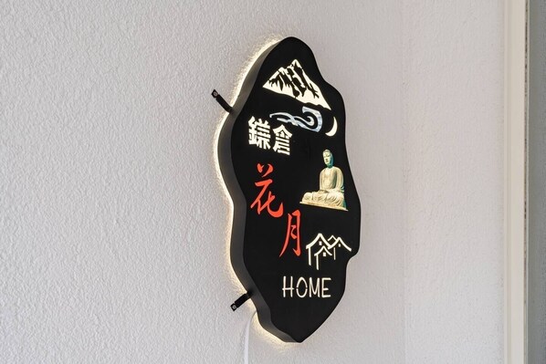 A black sign with white and red text and a Buddha statue, mounted on a white wall. - Max. 12 people OK! Less than 15 minutes walk to the station and the sea! A house in a good location in Kamakura! (鎌倉市大町)