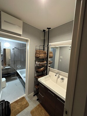 A modern bathroom with a white sink, dark wooden cabinets, a towel rack with folded towels, and a shower area. - Max. 12 people OK! Less than 15 minutes walk to the station and the sea! A house in a good location in Kamakura! (鎌倉市大町)