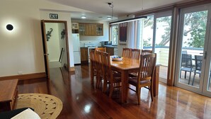 A dining area with a wooden table and chairs, a kitchen in the background, and a sliding glass door leading to an outdoor patio.