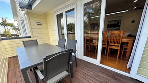 A patio with a table and chairs, a sliding glass door leading to an indoor dining area with wooden furniture.