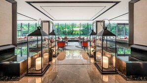 A modern interior with a glass railing, seating area, and a view of greenery outside. - Chongqing Ronghui Grand Hotel (Chongqing)