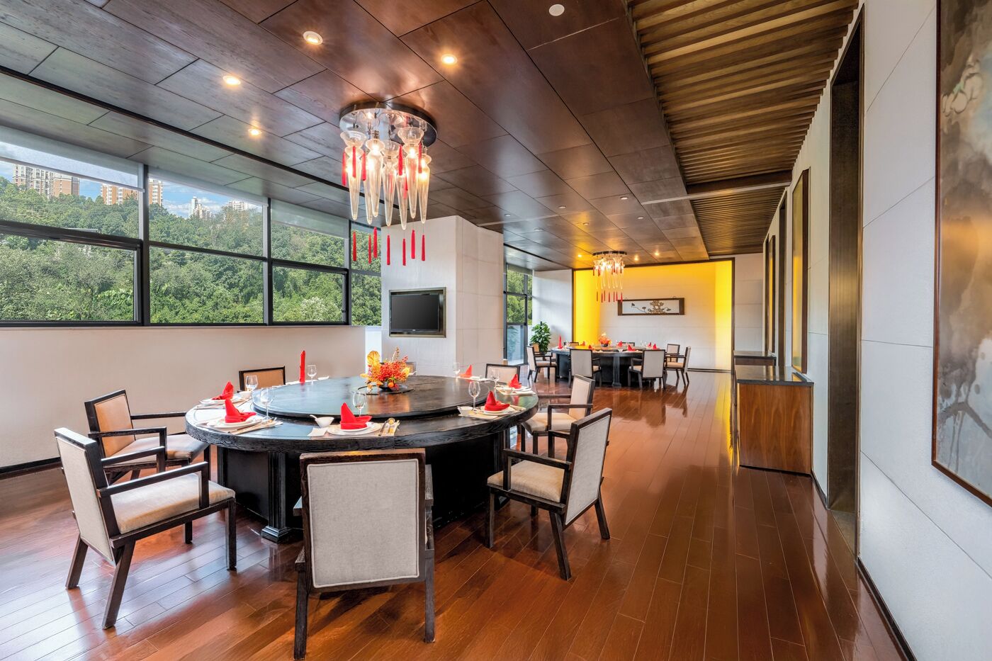 A modern dining area with a round table, chairs, and a chandelier.