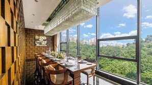 A dining area with a long table set for six, large windows offering a cityscape view, and a modern chandelier. - Chongqing Ronghui Grand Hotel (Chongqing)