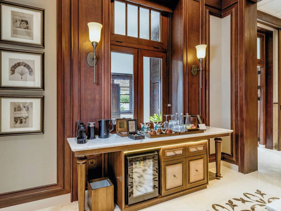 A hotel reception area with a wooden reception desk, framed pictures on the wall, and a coffee station.