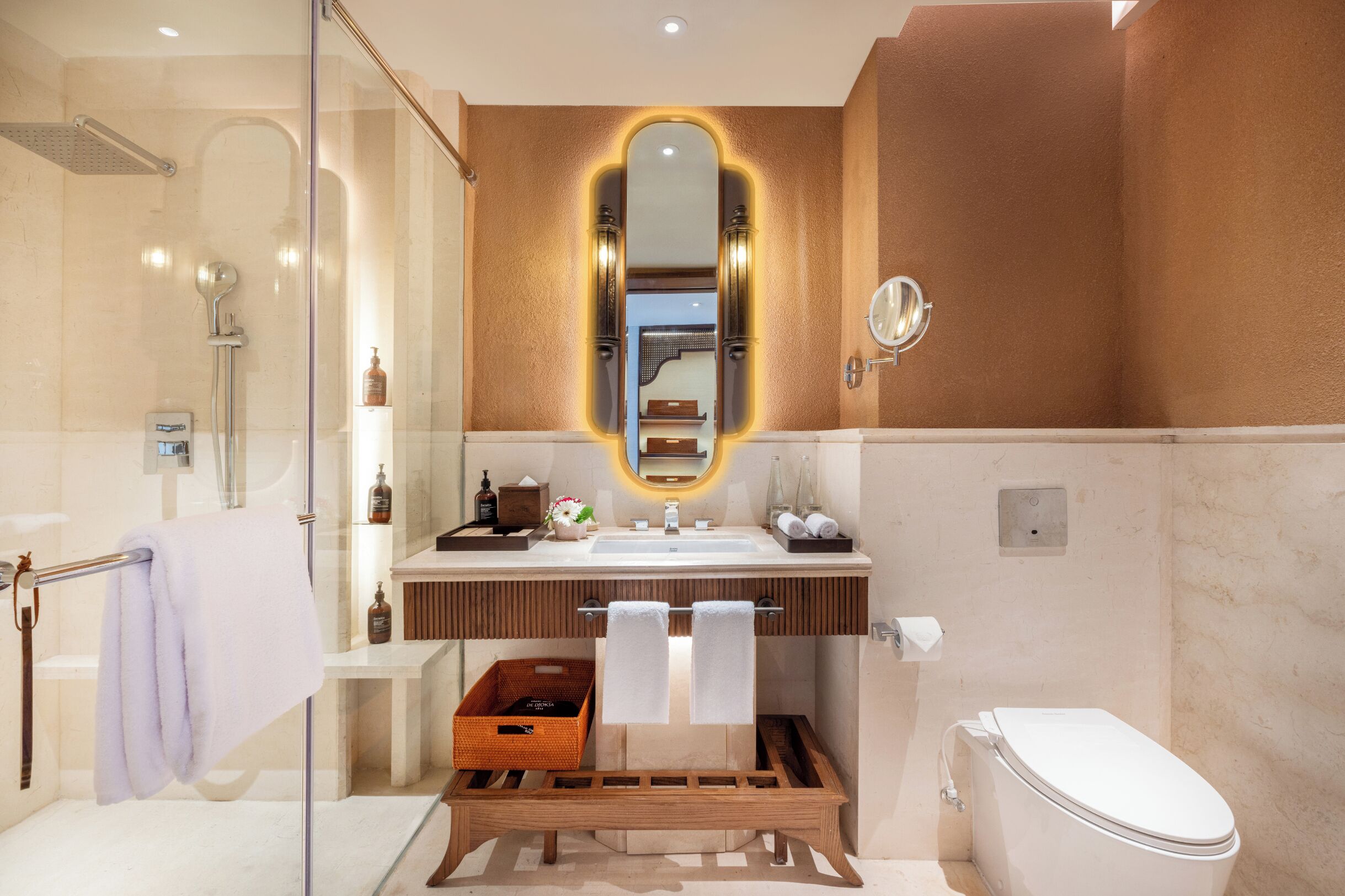 Un baño moderno con cabina de ducha de vidrio, tocador con espejo y un inodoro.