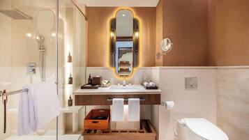 Un baño moderno con cabina de ducha de vidrio, tocador con espejo y un inodoro.