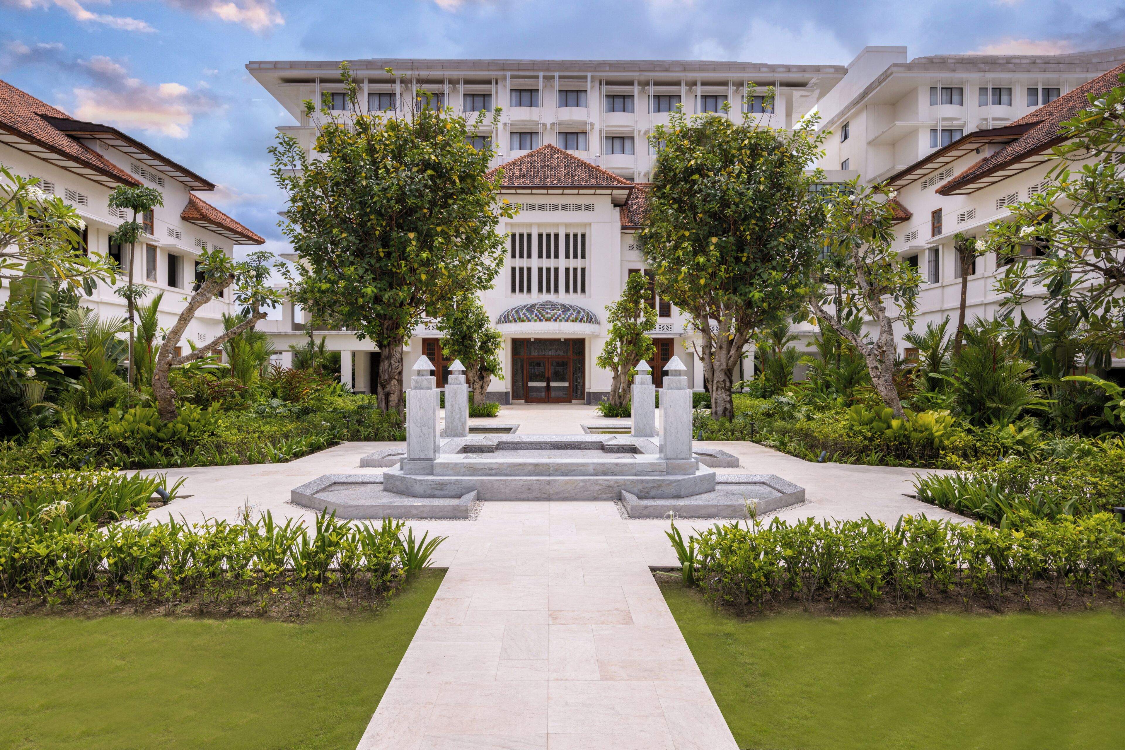 A hotel with a central courtyard, surrounded by lush greenery and a tiled walkway.