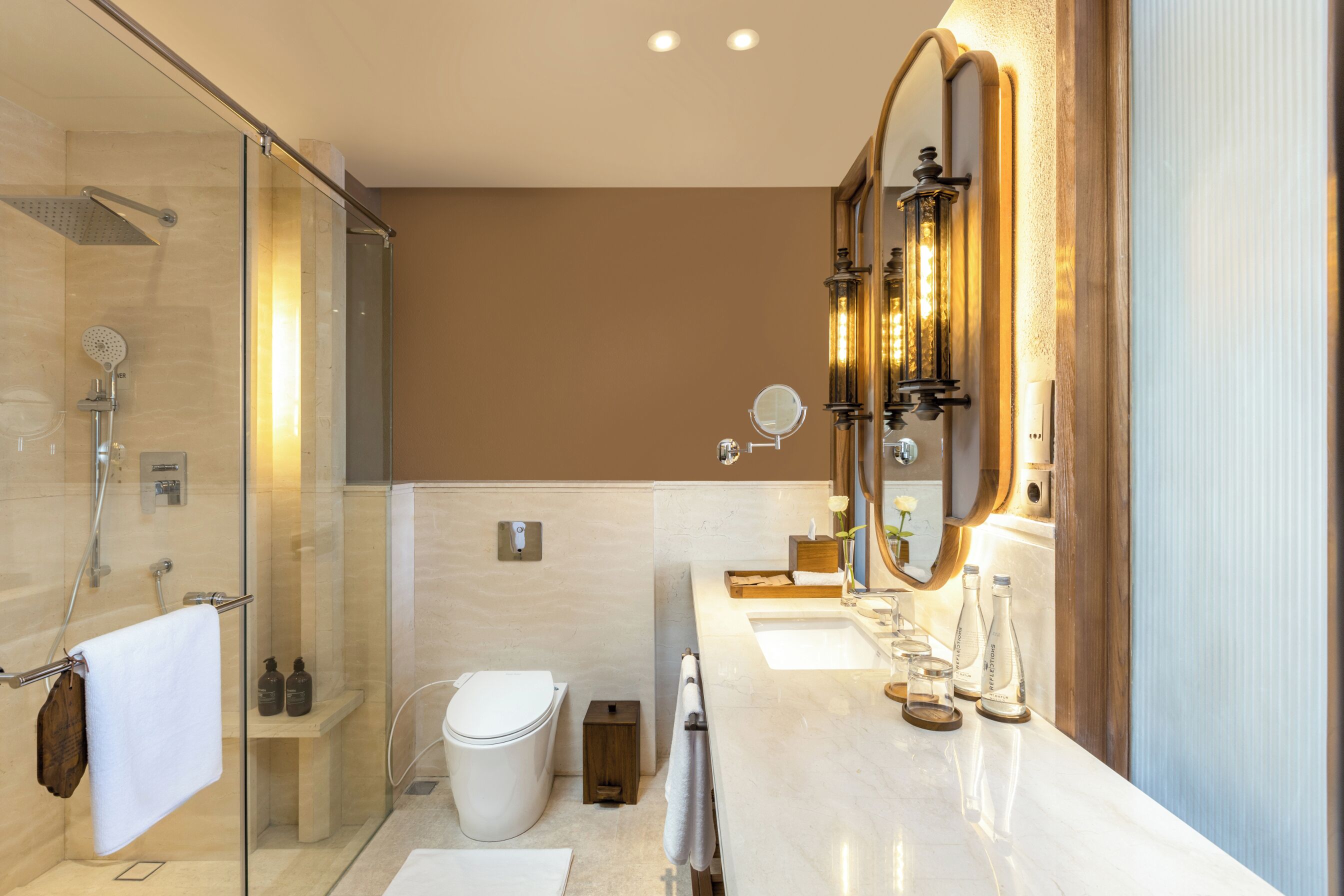 A modern bathroom with a glass shower enclosure, a toilet, a vanity with a large mirror, and a sink.