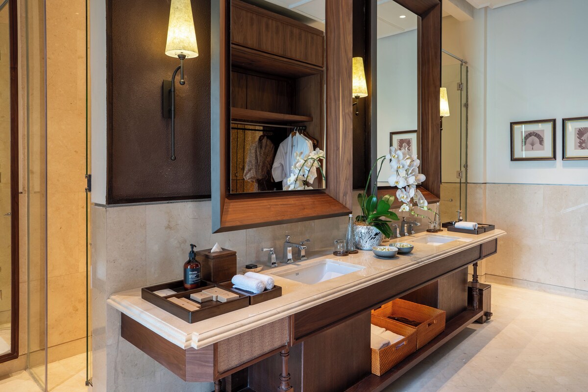 A modern bathroom with a double sink vanity, a large mirror, and a wooden cabinet above the sink.
